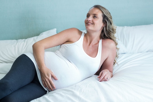 Mujer embarazada tocando su vientre en su dormitorio
