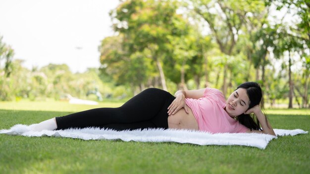 Mujer embarazada tocando el vientre en el parque de la ciudad Embarazada Relajarse y hacer ejercicio Hermosa foto tierna del embarazo