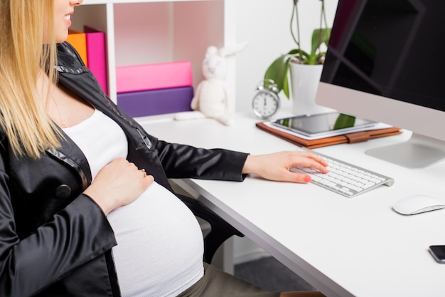 Mujer embarazada trabajando en computadora