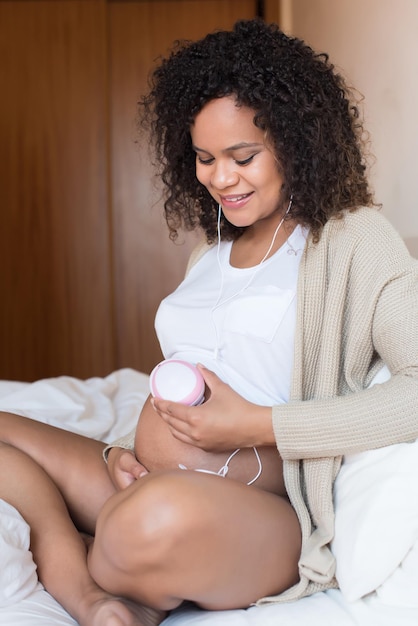 Mujer embarazada usando un doppler fetal en casa