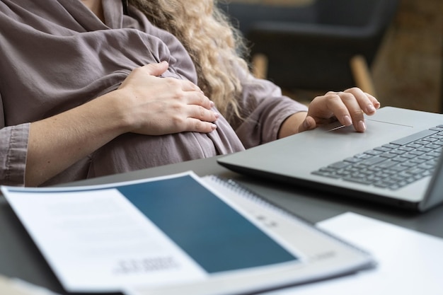 Mujer embarazada usando laptop en el trabajo