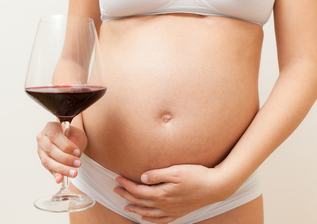 Mujer embarazada con vaso de vino tinto