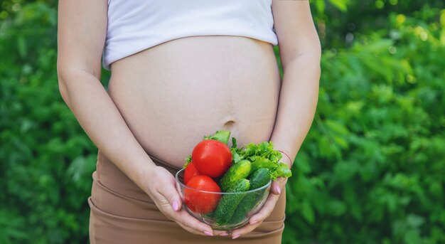 Una mujer embarazada con verduras en sus manos. Enfoque selectivo. comida.