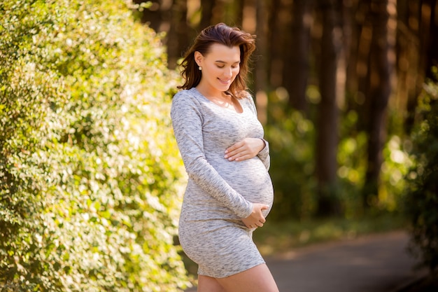 mujer embarazada con vestido posando en la naturaleza