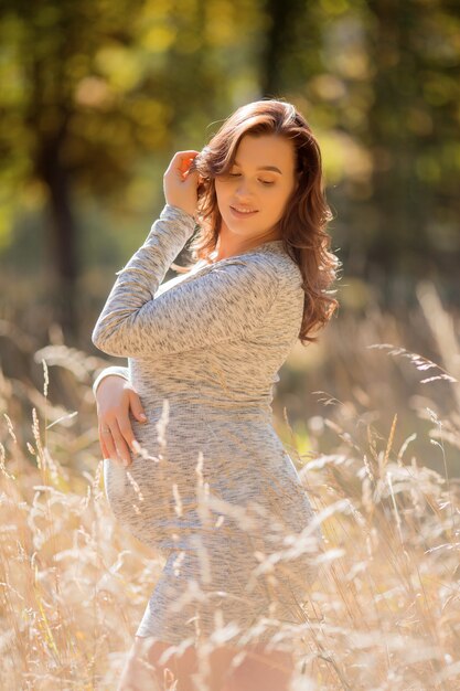 mujer embarazada con vestido posando en la naturaleza