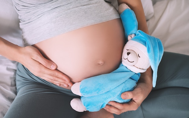 Mujer embarazada vientre con osito de peluche concepto de embarazo de maternidad y paternidad