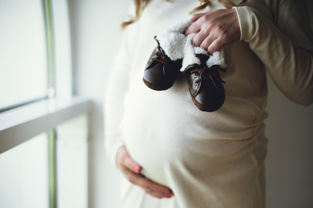 Mujer embarazada con zapatitos de bebé