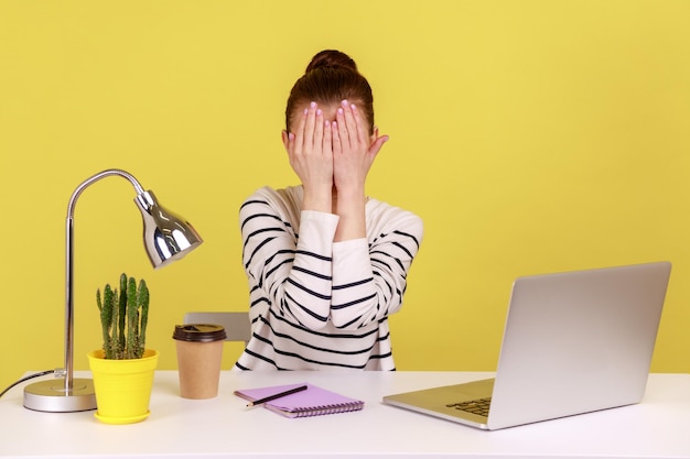 Mujer emocionada cerrando los ojos con la mano para evitar ver algo vergonzoso trabajando desde la oficina en casa