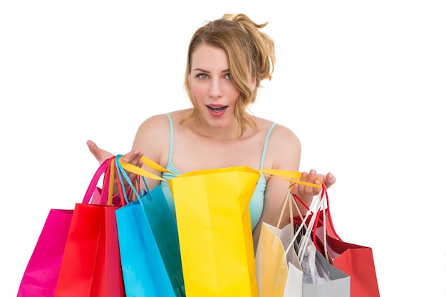 Mujer emocionada mirando a la cámara con muchos bolsos de compras