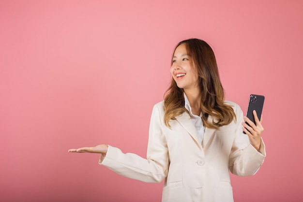 Mujer emocionada sosteniendo la pantalla en blanco del teléfono móvil presentando el producto con la palma de la mano vacía