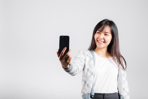 Mujer emocionada sosteniendo el teléfono inteligente para disparar la cámara frontal de la foto selfie