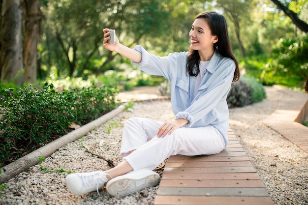 Mujer emocionada tomando una selfie en el camino en un parque público