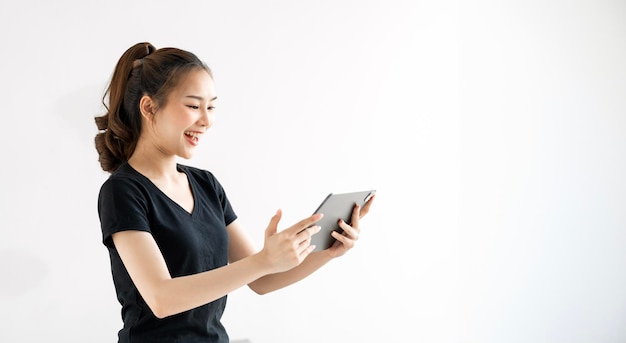 Mujer emocionada usando una tableta digital de pie sobre un fondo blanco