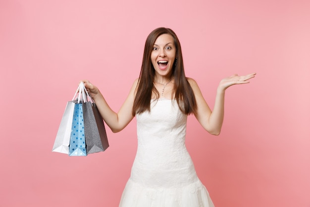 Mujer emocionada en vestido blanco extendió las manos sostienen bolsas de paquetes multicolores con compras después de ir de compras