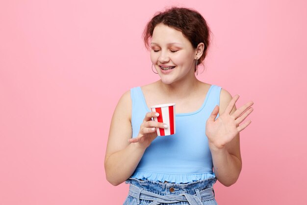 Mujer emocional alegre con vaso desechable de fondo rosa de bebida