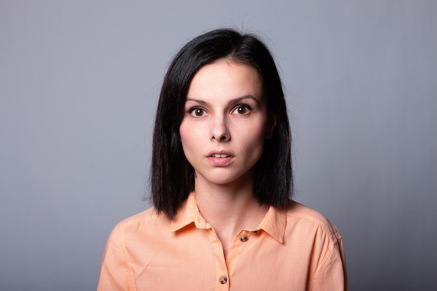 mujer emocional en camisa naranja fondo gris