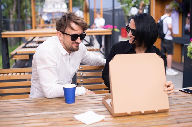 Una mujer emocional y un hombre miran una caja de pizza abierta