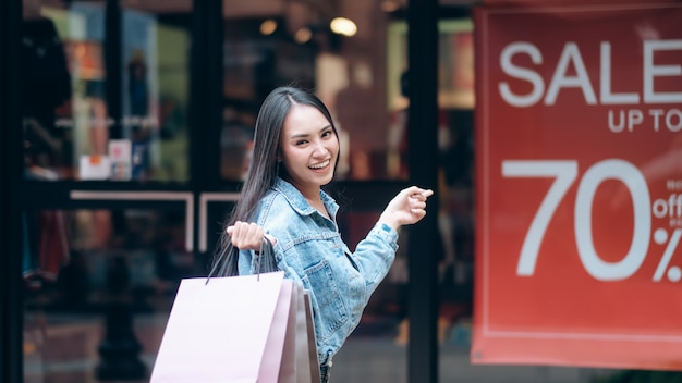 Mujer emocionante en compras apuntando al tablero de venta.