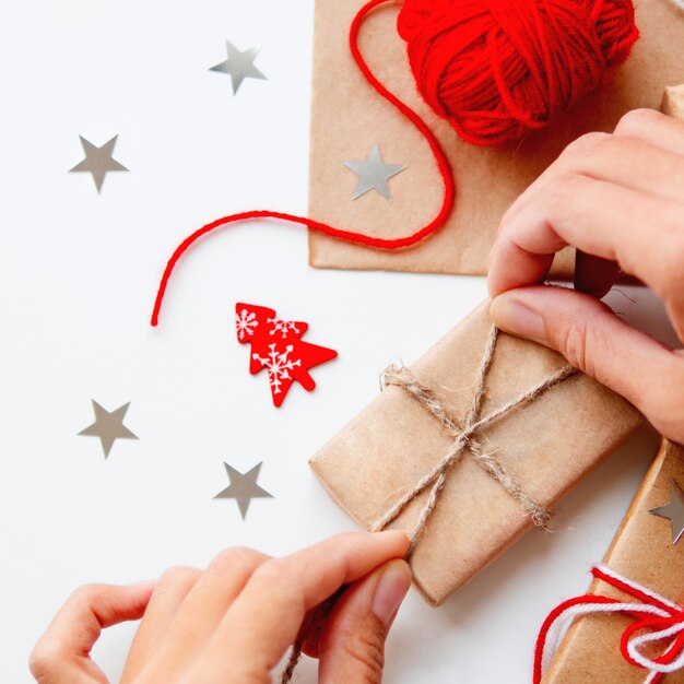 Mujer empaca regalos de Navidad y Año Nuevo en papel artesanal