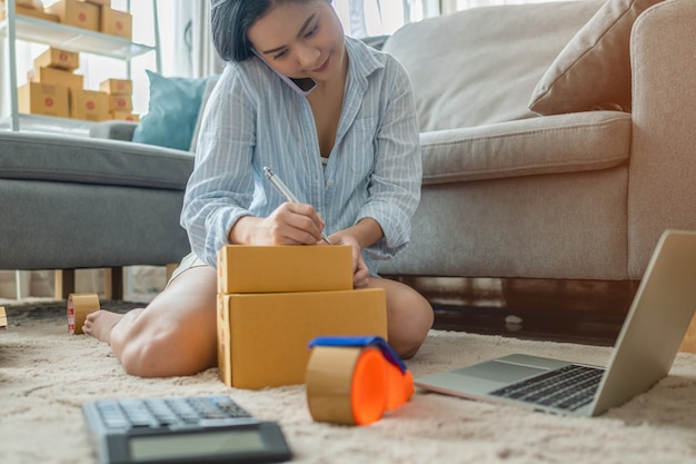 Foto mujer empaca y vende productos en línea. pequeños negocios. trabajar desde casa.sme vendiendo trabajo en concepto de casa. grupo.