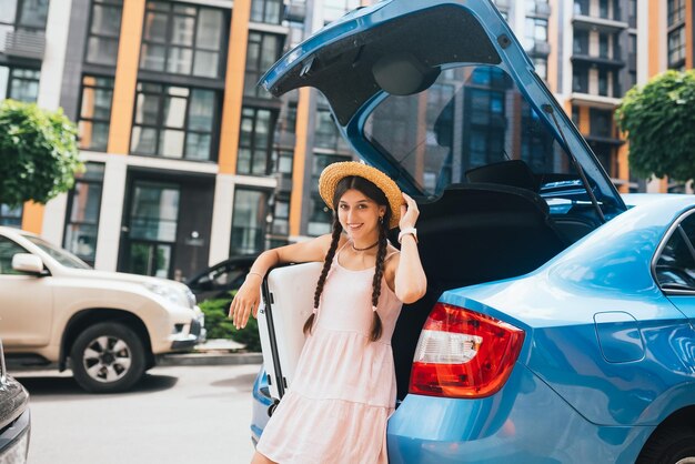 Mujer empacando su maleta en el maletero del coche