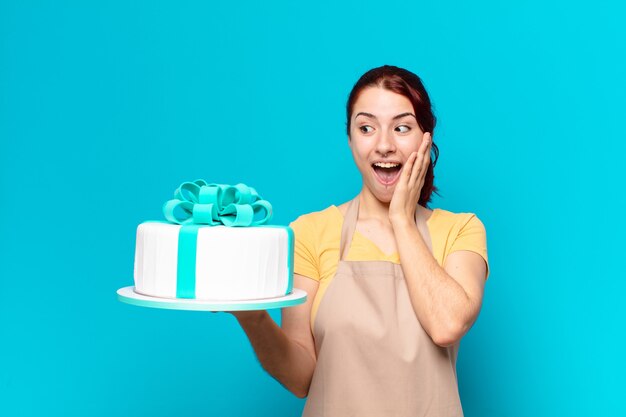 Mujer empleada de panadería bonita con un pastel de cumpleaños