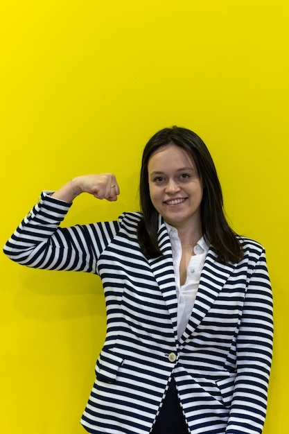 Foto una mujer empoderada que muestra su bíceps sobre un fondo amarillo
