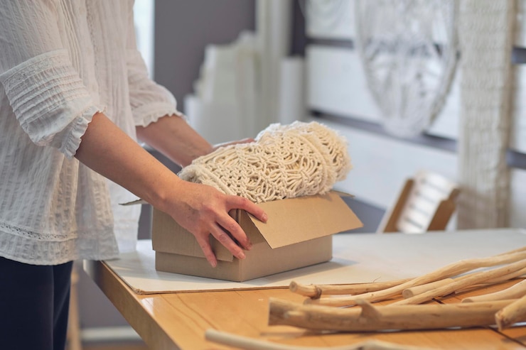 Foto mujer empresaria envasa un producto hecho a mano en una caja de cartón entrega de mercancías para