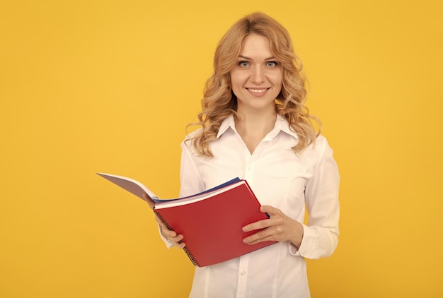 Mujer empresaria rubia feliz con camisa blanca haciendo notas en el bloc de notas o en el cuaderno ejecutivo