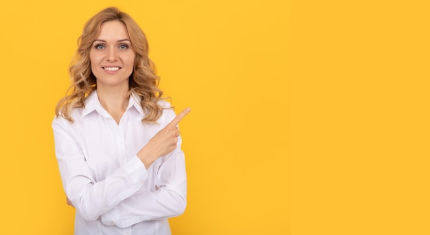 Mujer empresaria rubia feliz con camisa blanca señalando con el dedo el anuncio del espacio de copia