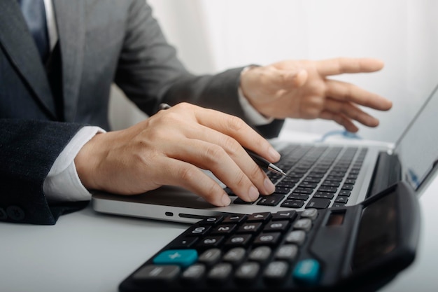 Mujer empresaria usando una calculadora con un bolígrafo en la mano calculando los gastos financieros en la oficina en casa