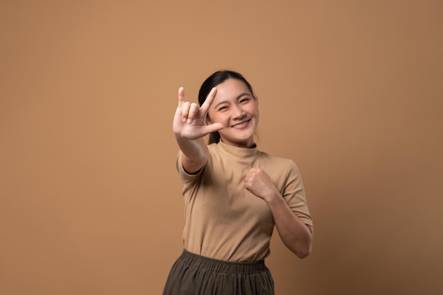 Mujer enamorada haciendo símbolo de amor aislado sobre fondo beige