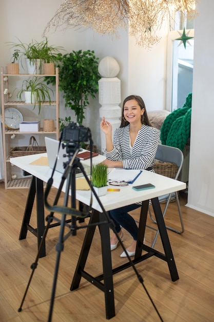 Foto mujer encantada positiva sonriendo a la cámara mientras graba un video