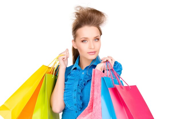 Mujer encantadora con bolsas de la compra sobre blanco