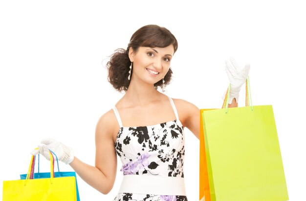 Mujer encantadora con bolsas de la compra sobre blanco