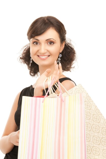 Mujer encantadora con bolsas de la compra sobre blanco