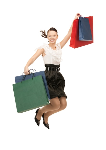 Mujer encantadora con bolsas de la compra sobre blanco