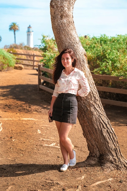 Una mujer encantadora camina por el paseo marítimo con una vista del faro de Point Vicente en Los Ángeles