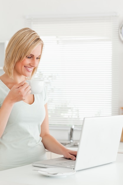 Mujer encantadora con una taza de café y una computadora portátil