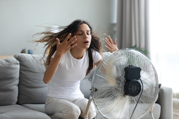 La mujer encendió el ventilador agitando las manos para refrescarse.