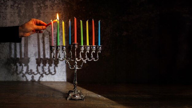 Foto una mujer enciende una vela en una menorá para hanukkah fiesta religiosa judía concepto de hanukkah