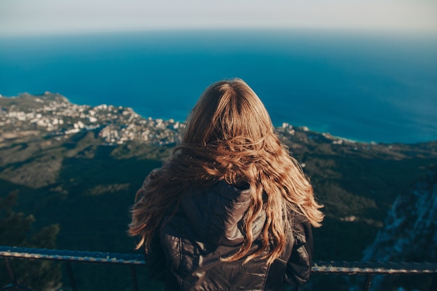 La mujer se encuentra en el borde de un brillante. Viaje por las montañas