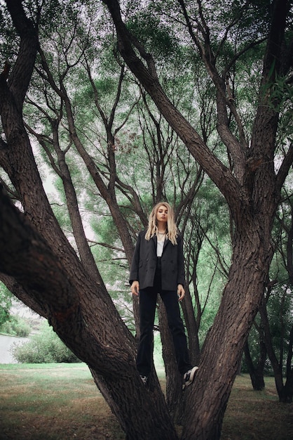 Una mujer se encuentra en un bosque con un árbol en primer plano y la palabra árbol a la izquierda.