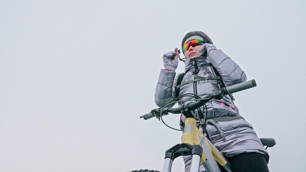 Mujer se encuentra cerca de su bicicleta en el hielo El ciclista chica se detuvo a r