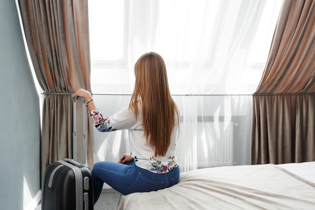 Mujer se encuentra cerca de la ventana en la habitación del hotel en el tiempo de la mañana