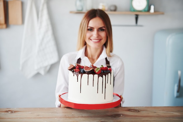 La mujer se encuentra en el interior de la cocina con tarta casera.