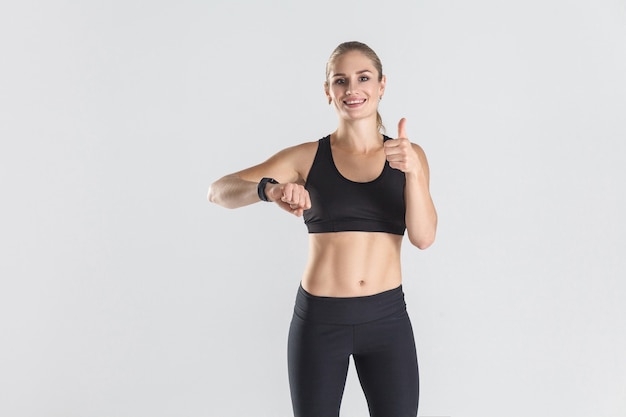 Mujer de energía mostrando los pulgares para arriba a la cámara foto de estudio