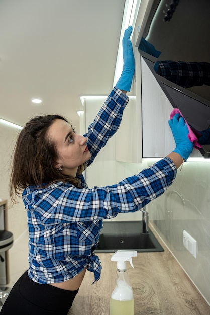 Mujer enérgica limpia la cocina con medios modernos para limpiar la suciedad en lugares inaccesibles