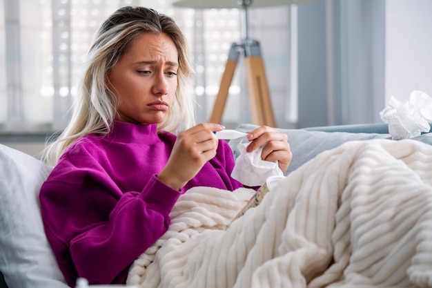 Mujer enferma acostada en la cama con fiebre alta. Gripe fría y migraña.