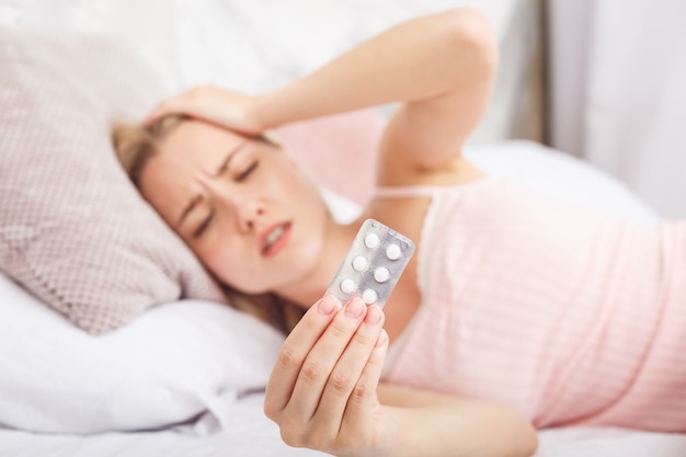 Mujer enferma acostada en la cama con fiebre alta